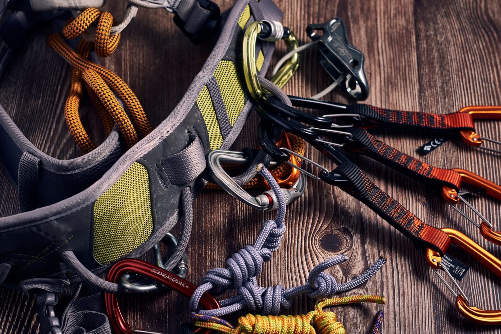 A closeup shot of many colorful climbing carabiners and knots on a wooden surface