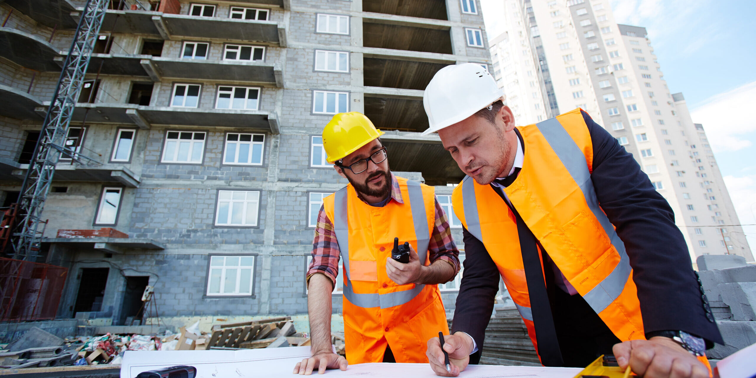 Modern engineer pointing at sketch in blueprint while explaining it to colleague